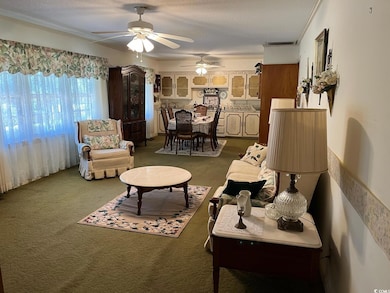 Living room with carpet, visible vents, a textured ceiling, and ornamental molding
