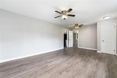 Empty room featuring a ceiling fan, wood finished floors, and baseboards