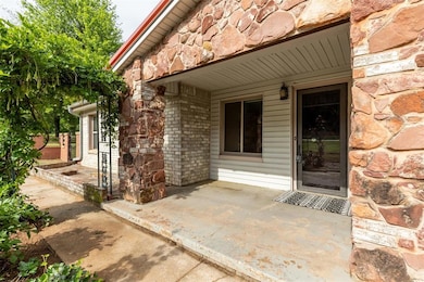 Doorway to property featuring stone siding and a patio area