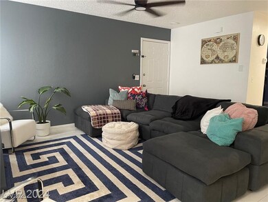 Living room with a ceiling fan and a textured ceil