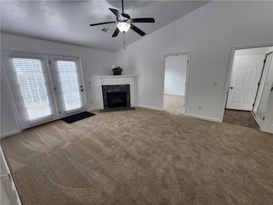 Unfurnished living room with carpet flooring, baseboards, a ceiling fan, a high end fireplace, and high vaulted ceiling