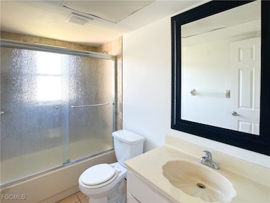 Bathroom with vanity, enclosed tub / shower combo, and tile patterned flooring