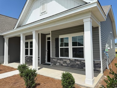 View of home's exterior featuring roof with shingles, stone siding, covered porch, and board and batten siding
