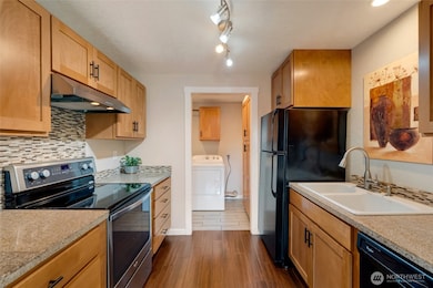 Galley kitchen with light wood and all black appliances give the kitchen beautiful contrast.