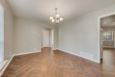 Empty room featuring baseboards and a chandelier