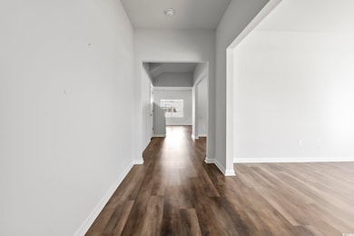 Corridor featuring dark wood-style floors and baseboards