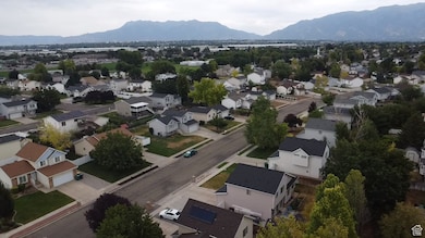 Aerial view of property and surrounding area featuring a mountain backdrop and nearby suburban area