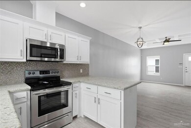 Kitchen featuring decorative backsplash, white cabinets, a peninsula, light wood finished floors, and stainless steel appliances