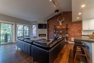 Living room featuring hardwood / wood-style floors, a fireplace, vaulted ceiling, plenty of natural light, and track lighting