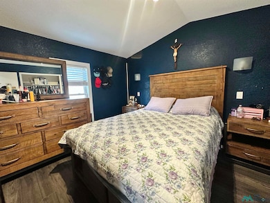 Bedroom with vaulted ceiling and dark wood-style flooring