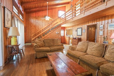 Living room featuring wooden ceiling, beam ceiling, wooden walls, ceiling fan, and wood finished floors