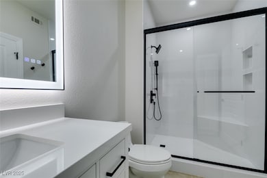 Bathroom with toilet, a shower stall, vanity, and
