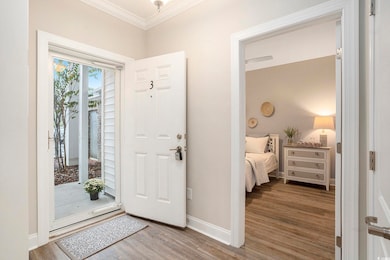 Foyer with crown molding and wood finished floors
