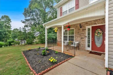 Property entrance with stone, landscaping, and covered porch.