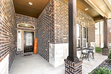 A closer look at the inviting front porch shows off a rich dark-stained door with wrought iron detailing, complemented by the covered side porch, enhancing the home's welcoming exterior.