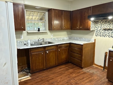 Kitchen featuring dark wood finished floors, freestanding refrigerator, dark brown cabinets, and light countertops
