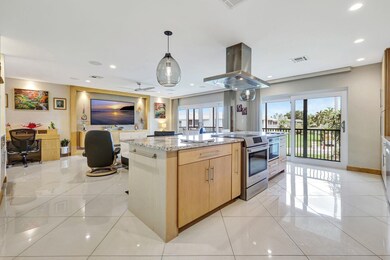 Kitchen featuring stainless steel range with electric cooktop, island range hood, light brown cabinets, light stone countertops, and light tile patterned floors