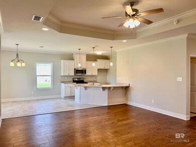 Kitchen featuring stainless steel appliances, ceiling fan with notable chandelier, light wood-type flooring, and white cabinets