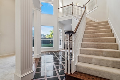 Entrance foyer with plenty of natural light, decorative columns, a high ceiling, and stairs