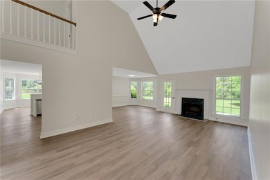Unfurnished living room featuring high vaulted ceiling, ceiling fan, a fireplace, and plenty of natural light