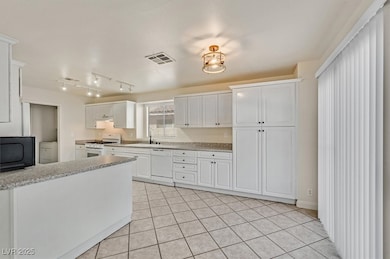 Kitchen with white cabinetry, white appliances, light tile patterned flooring, rail lighting, and washer / clothes dryer