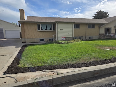Single story home with brick siding, a chimney, a front yard, and a garage
