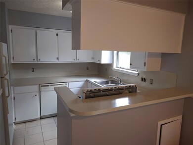 Kitchen featuring white appliances, a peninsula, white cabinetry, light countertops, and light tile patterned floors