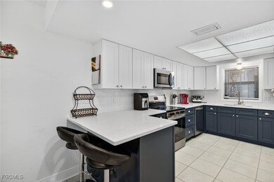Kitchen with white cabinets, a breakfast bar, stainless steel appliances, a peninsula, and backsplash