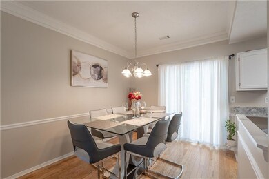 Dining area featuring light wood-style flooring, ornamental molding, and a chandelier