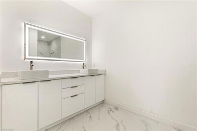 Bathroom with marble finish floors, double vanity, and a marble finish shower