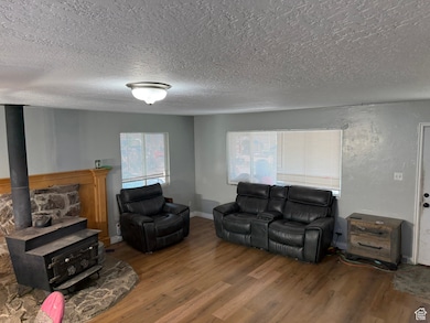 Living room with wood finished floors, a textured ceiling, and a wood stove