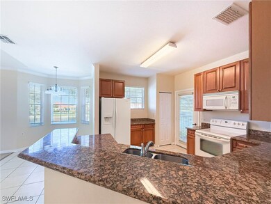 Kitchen with white appliances, brown cabinets, lig