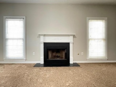 Detailed view of carpet flooring, a fireplace with flush hearth, and baseboards