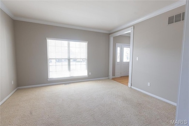 Spare room with ornamental molding and light carpet