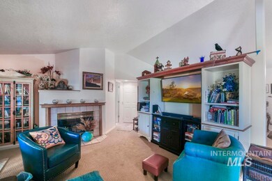 Carpeted living area with a tiled fireplace and vaulted ceiling