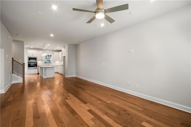 Unfurnished living room with wood finished floors, baseboards, a ceiling fan, recessed lighting, and stairs