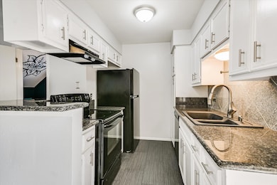 Kitchen featuring black electric range oven, white cabinets, and dark stone counters