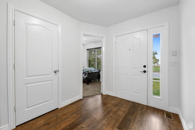 Entrance foyer with dark wood-style floors and baseboards