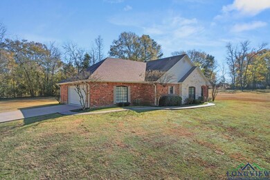 View of front of home featuring concrete driveway, an attached garage, a front lawn, and brick siding