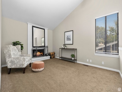 Sitting room featuring carpet, a fireplace, and vaulted ceiling