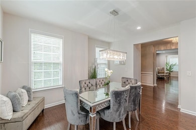 Dining room with a chandelier, wood finished floors, baseboards, and recessed lighting