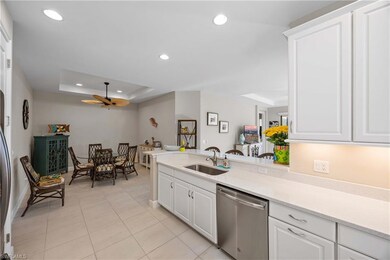 Kitchen with a raised ceiling, white cabinetry, a peninsula, stainless steel appliances, and light stone countertops