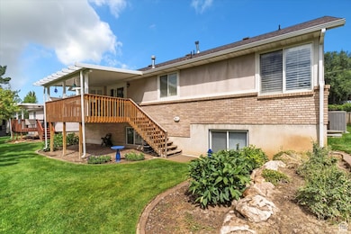 Rear view of house featuring stairway, brick siding, a deck, and a yard