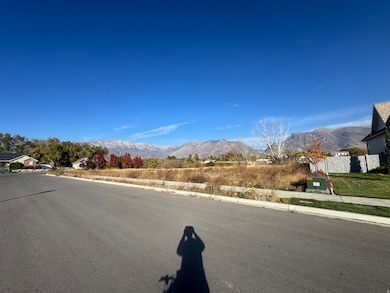 View of asphalt road featuring a mountain view, sidewalks, and curbs