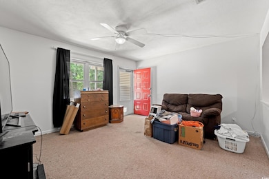 Sitting room with ceiling fan, carpet floors, and a textured ceiling