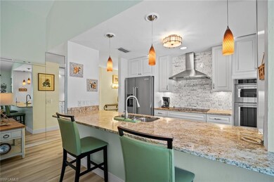 Kitchen featuring a sink, wall chimney exhaust hood, visible vents, light stone countertops, and appliances with stainless steel finishes