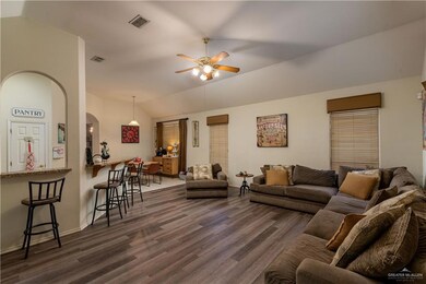 Main living room featuring dark wood-type flooring, ceiling fan, and vaulted ceiling