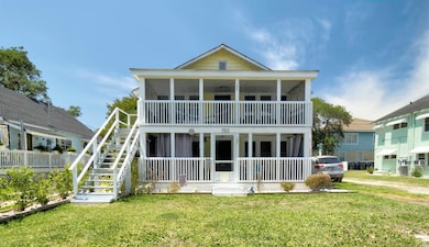 Rear view of property with covered porch, a yard, and stairway