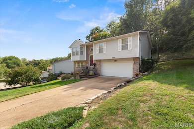 Bi-level home with a front lawn, a garage, driveway, and a chimney