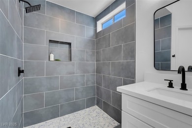 Full bath featuring tiled shower and vanity